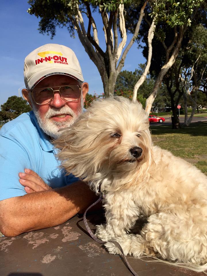 a man with a hat and eyeglasses next to a furry dog