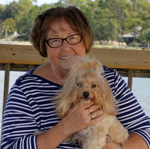 a woman with glasses holding a brown dog