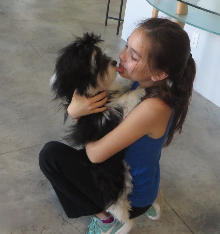 a girl hugging a dog licking her chin