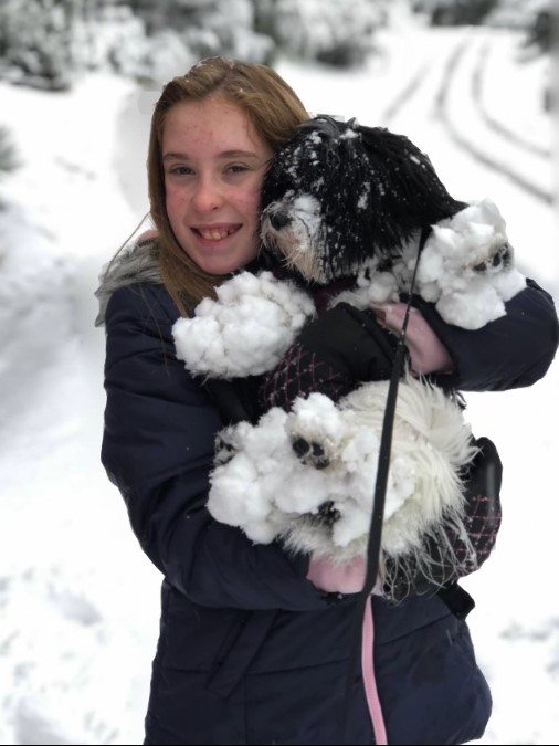 a girl hugging a dog covered in snow